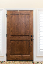 The Interior View Of A Classic Brown Stained Solid Wood Front Door With Windows And Plantation Shutters On Each Side