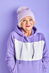 senior woman in hat and colourful pullover posing at camera in studio, she is excited. portrait