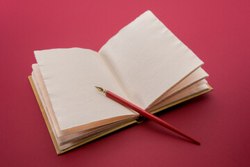 Fototapete - Vintage red pen with gold nib on open antique leather hardcover notebook  on cardinal red color background