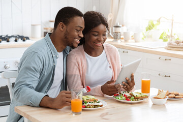 Happy African American Couple Having Breakfast And Using Digital Tablet In Kitchen