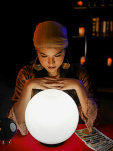 Asian Woman Fortune Teller Using Magical Occult Divine Power Crystal Call To Forecast Luck On Red Table. 