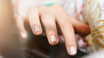 Wall Mural - young woman hand with manicure types on laptop touchpad