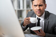 © LIGHTFIELD STUDIOS - thoughtful businessman holding coffee cup at workplace, blurred foreground