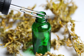 Macro close up of green isolated dropping pipette medical cannabinol cpd oil bottle with dried cannabis buds, white background