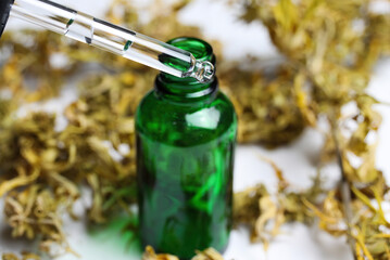 Macro close up of green isolated dropping pipette medical cannabinol cpd oil bottle with dried cannabis buds, white background