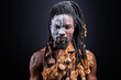 african shirtless guy with colourful make-up isolated on dark studio background, young male tribal has ethnic traditional chain