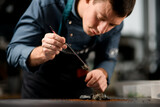 Fototapeta Desenie - Close-up view on male chef holding tweezers with ingredient for preparing fusion cuisine dish