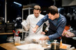 two male chefs are cooking in the kitchen