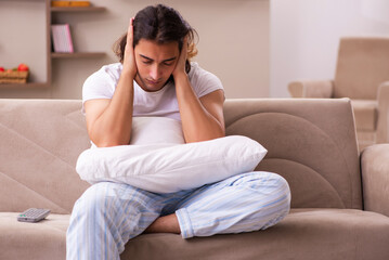 Wall Mural - Young lazy man in oversleeping concept at home