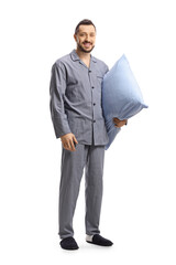 Wall Mural - Young man in pajamas holding a pillow and smiling at camera