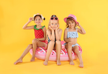 Canvas Print - Cute little children in beachwear with bright inflatable ring on yellow background