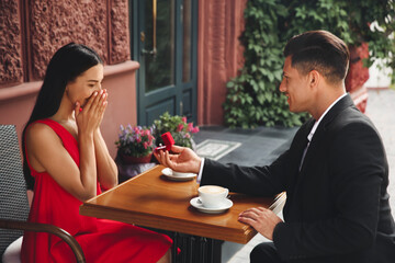 Poster - Man with engagement ring making proposal to his girlfriend in outdoor cafe