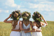 Leinwandbild Motiv Young women wearing wreaths made of beautiful flowers in field on sunny day, back view