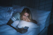 © New Africa - Young woman using smartphone in bed at night. Nomophobia and sleeping disorder problem