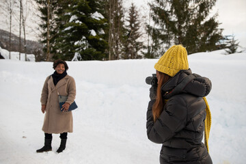 Professional photographer takes a photo of a lady in the mountains in a snowy landscape.