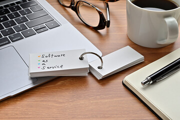 Poster - there's a laptop computer, a notebook, a pen and an open vocabulary book on the desk. the word softw