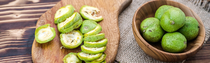 Natural unprocessed green ugly walnuts Cut into slices and lying on cutting wooden vintage board. ingredients for tincture of green walnuts. zero waste. Soft focus