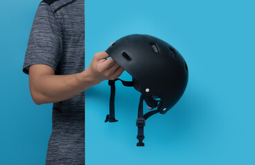 Male hand holding black helmet for sports on blue background,copy space for text