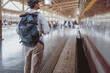 © Garun Studios - Asian man traveler with backpack in the railway, Backpack  and wearing hat at the train station with a traveler. Travel concept. Man traveler tourist walking at train station.