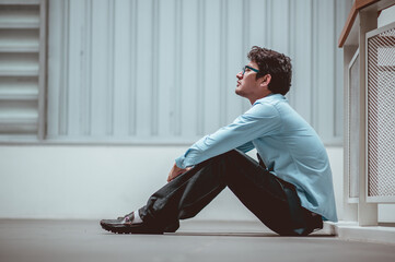 Businessman sitting on the floor after failure and layoff. Man unemployed from company sitting sad outside at overpass background. Men fired from job. Stress manager sit alone.