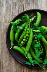 Green peas in a plate on a old wooden  background. View from above.