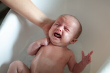 Newborn Baby Is Being Bathed By His Mother. Newborn Baby Crying In Bath Time