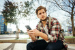 © Rymden - Portrait of modern young man with smartphone on a street