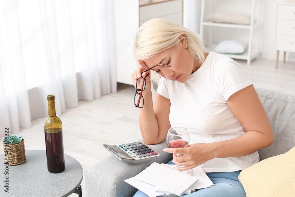 Stressed mature woman drinking wine at home
