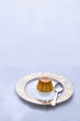 © Atikah - Caramel pudding kept on a plate with a silver spoon