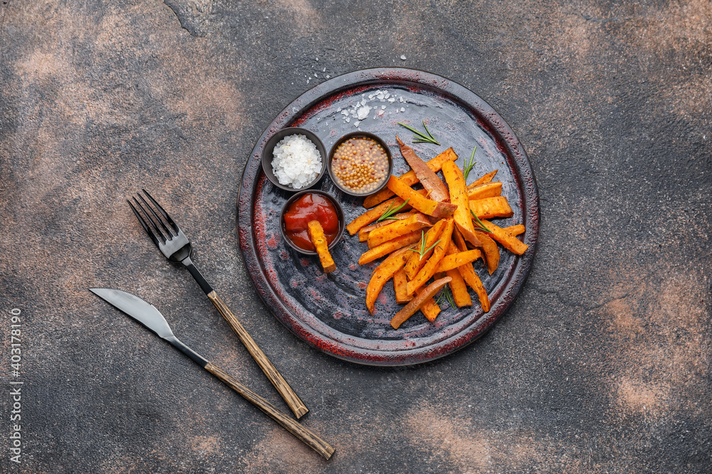 Board with tasty cooked sweet potato on grunge background