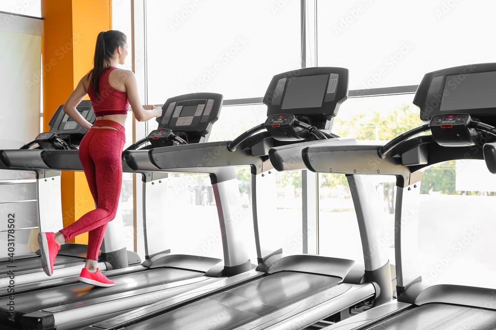 Young woman training on treadmill in gym