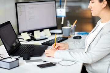 business, technology and people concept - businesswoman with notebook and laptop computer working at office