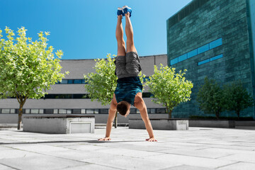 Poster - fitness, sport, training and lifestyle concept - young man exercising and doing handstand outdoors