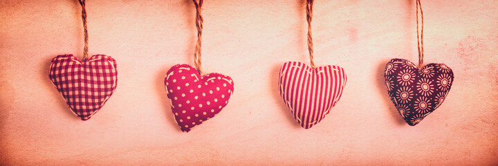Wall Mural - four red fabric hearts on vintage panoramic background with copy space