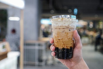 Wall Mural - Bubble Milk tea, man holding a plastic cup of bubble or boba milk tea with brown sugar and topped with cheese cream.