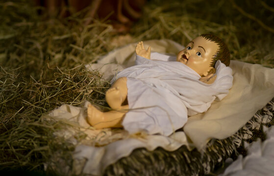 A Figurine of Baby Jesus Lying on the Hay in a Stable with White Clothes on at the Nativity Scene at Christmas