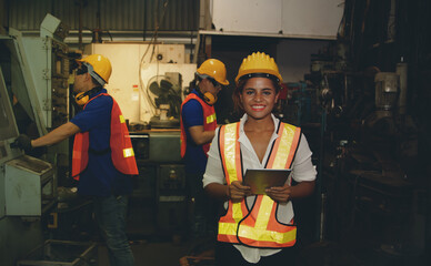 Technician, an African-American female machine control engineer, engineering works as a team with a group of men in the manufacturing industry, producing machine parts with a smile and can lead.
