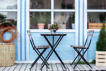 Wall Mural - Winter terrace with wicker baskets and green plants in pots on porch home. Wooden table and chairs on veranda of house. there is potted Christmas mistletoe on table in street cafe. Outdoor home decor