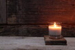 the burning luxury aromatic scented candle glass on the wooden table with background of vintage wooden wall of the cottage in the living room to creat relax ambient during christmas party celebration 
