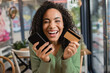 © LIGHTFIELD STUDIOS - cheerful african american woman laughing while holding smartphone and credit card