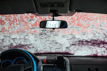 Foam on the windshield. Washing the dirt from the machine with foam. Self-service car wash.