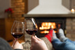 © artursfoto - Couple in love sitting in a cozy room with fire place on a sofa with glass of wine. Family and love concept.
