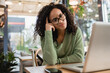 © LIGHTFIELD STUDIOS - pensive african american woman in glasses looking at laptop near smartphone on table