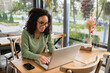 © LIGHTFIELD STUDIOS - African American freelancer in glasses using laptop in cafe