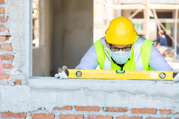 Wall Mural - Asain worker using water level meter measuring the wall builder on the construction site. Building  bubble level tool.