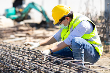 Wall Mural - Asian construction worker on building site. fabricating steel reinforcement bar. wearing surgical face mask during coronavirus and flu outbreak