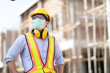 Wall Mural - Asian construction worker on building site. wearing surgical face mask during coronavirus and flu outbreak