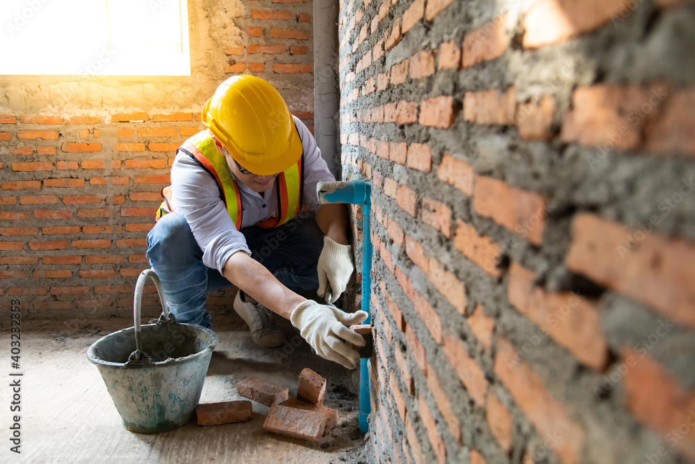 Man bricklayer installing bricks on construction site - obrazy, fototapety, plakaty 