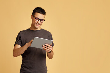 Work online, freelance, teacher and blogger. Smiling cute young male looks in tablet