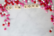 The Words So In Love  Written In Scrabble Tiles On A Marble Kitchen Counter Top Surrounded By Valentines Candy